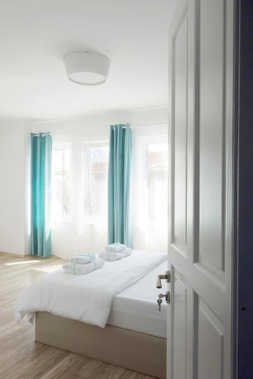 a bedroom with a bed with white sheets and blue curtains at Alicante Otel - Adult Only in Bozcaada