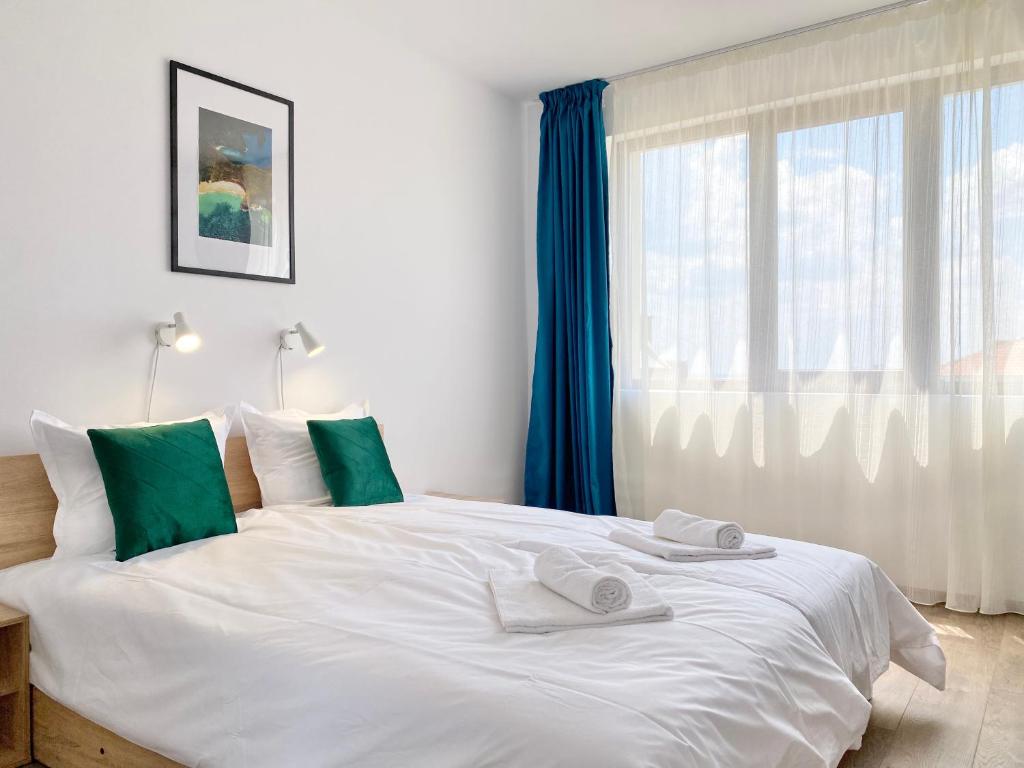 a bedroom with a large white bed with green accents at Central Seaview Apartments for 4 Guests in Sveti Vlas