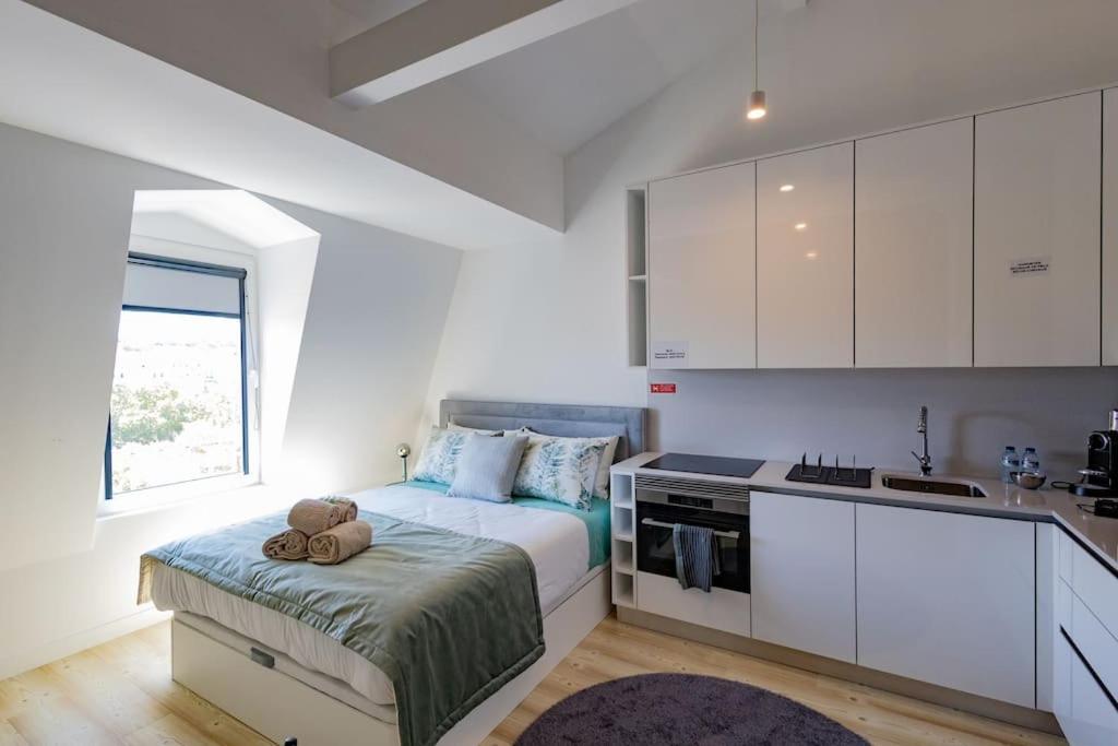sypialnia z łóżkiem oraz kuchnia z białymi szafkami w obiekcie Superb Central Lisbon Apartment w Lizbonie