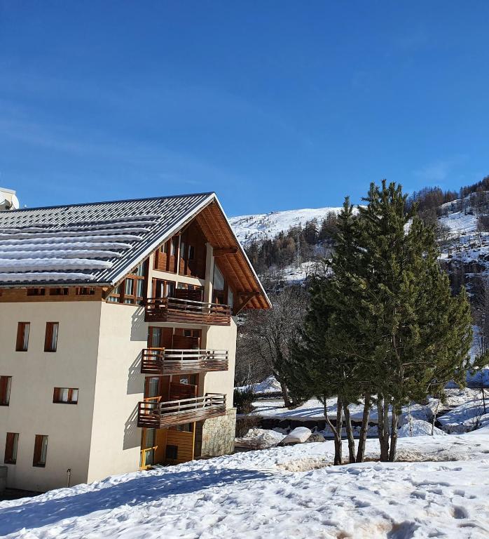 un bâtiment dans la neige avec un arbre dans l'établissement 2 pièces Valloire pied des pistes, à Valloire
