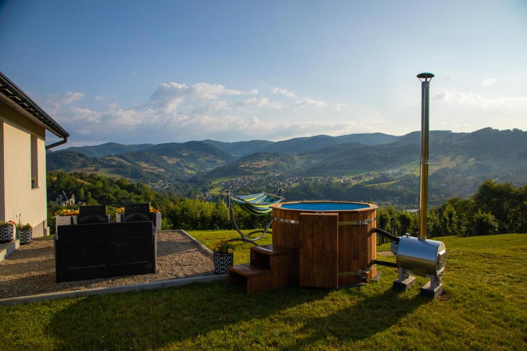 una bañera de hidromasaje y un barril en un patio con montañas en DOMEK NA WIERCHACH, en Piwniczna-Zdrój