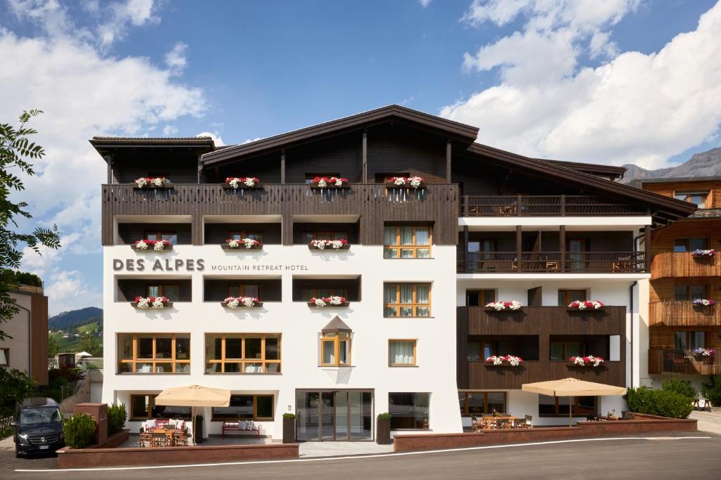 Un grand bâtiment blanc avec des fleurs sur les balcons dans l'établissement Hotel Des Alpes, à La Villa