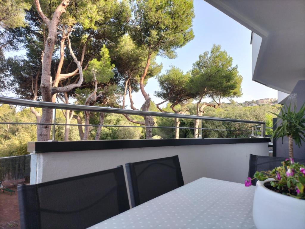 balcón con mesa, sillas y árboles en Vilar d'Aro Apartment, en S'Agaró