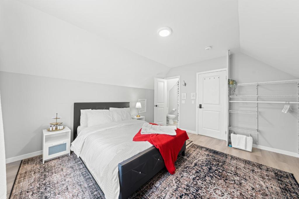 a white bedroom with a large bed with a red blanket at Close to mall with private toilet, Free Wi-Fi and Parking in Toronto