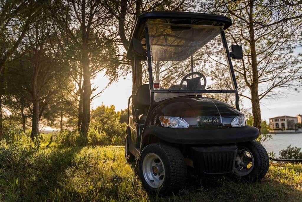 a golf cart parked in the grass in a field at Magnifique vue lac au Golf de Pont-Royal in Mallemort