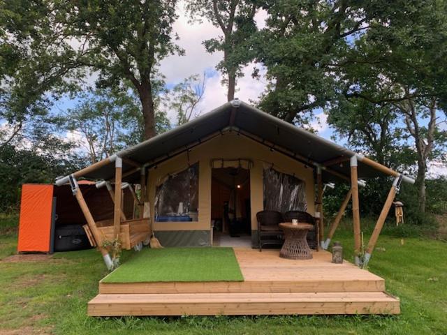 a black tent with a wooden porch in a field at IQBAL Hütte - Luxus Zelt, Whirlpool extra in Beverstedt