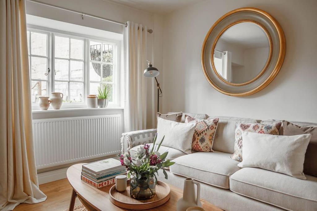 a living room with a couch and a mirror at Stylish Painswick Getaway in Painswick