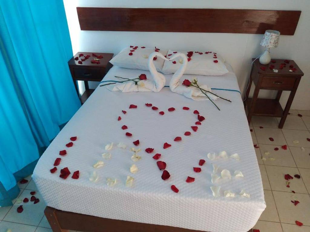 een bed met een hart gemaakt van rode pedalen bij HOTEL MAJESTIC ZARUMILLA in Zarumilla