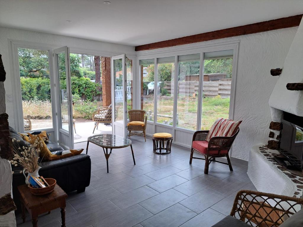 un salon avec des chaises et une cheminée dans l'établissement Maison Biscarrosse plage 500m de l océan, à Biscarrosse