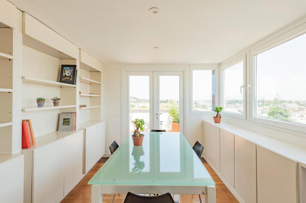 a dining room with a glass table and windows at Vatican View Apartment - Zen Real Estate in Rome