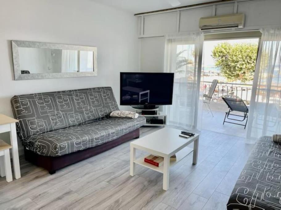 ein Wohnzimmer mit einem Sofa und einem Tisch in der Unterkunft Très bel appartement sur la plage avec grande terrace face à la mer! La Goelette in Vallauris