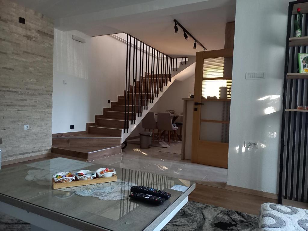 een woonkamer met een glazen tafel en een trap bij Golden House in Kolašin