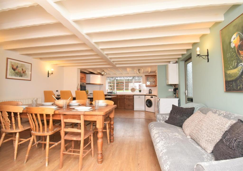 a dining room and living room with a table and a couch at Sagewood Cottage in Seaton