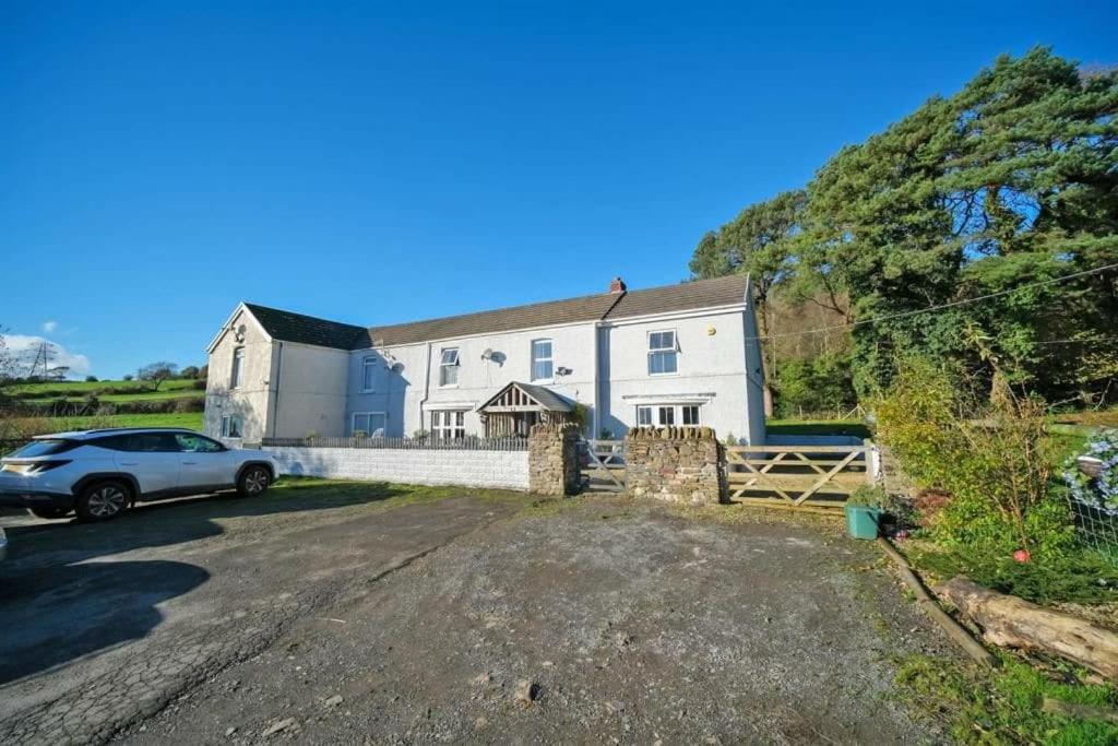 une grande maison blanche avec une voiture garée dans l'allée. dans l'établissement -- Huge -- 5-bedroom home & Private Gym by Tailored Accommodation, à Swansea