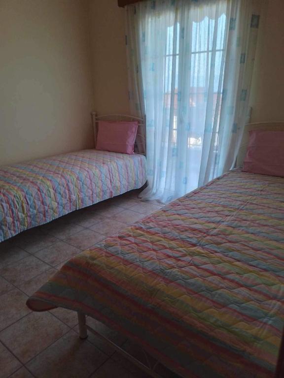 a bedroom with two beds and a window at Kali’s comfort in Karavomylos