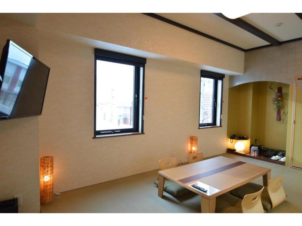 a living room with a table and some windows at QUEEN'S HOTEL CHITOSE - Vacation STAY 67734v in Chitose