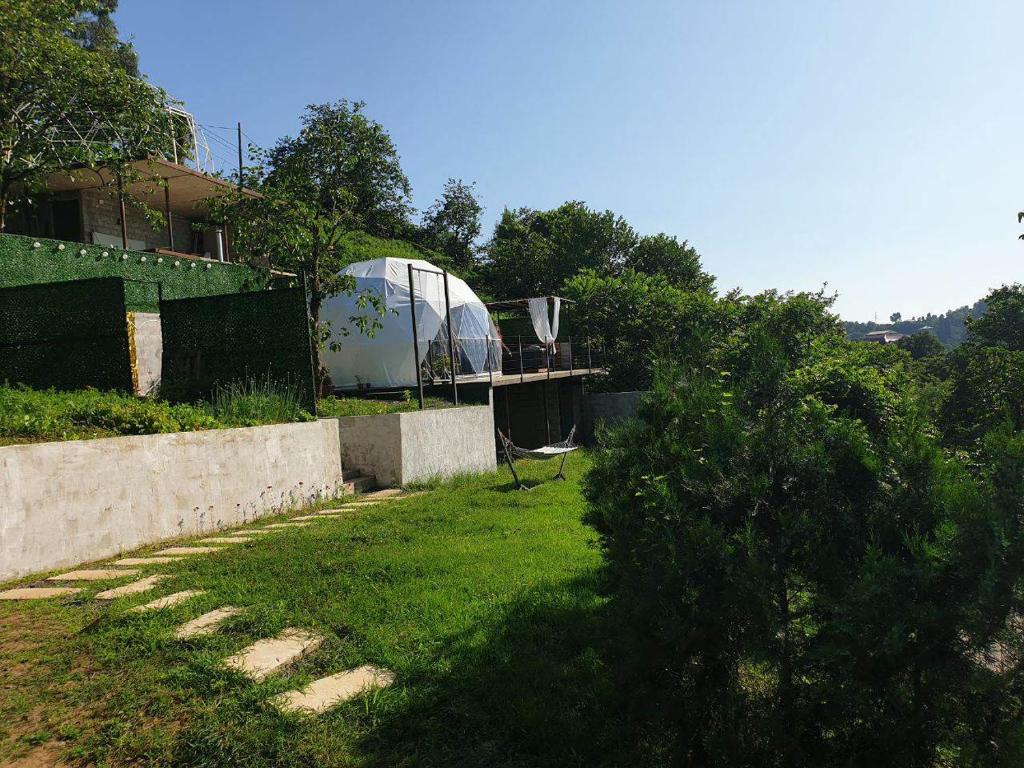 ogród z szklarnią w tle i podwórko z trawą w obiekcie Annas Glamping w mieście Batumi
