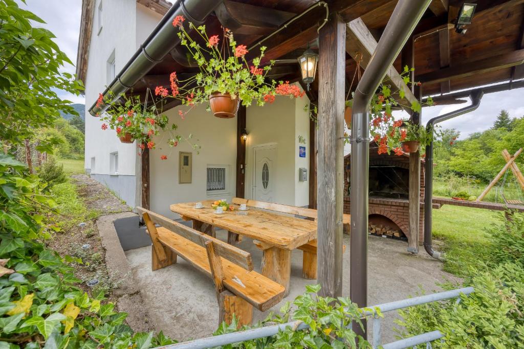 uma área de refeições exterior com uma mesa de madeira e um banco em Holiday home Veki*** em Korenica