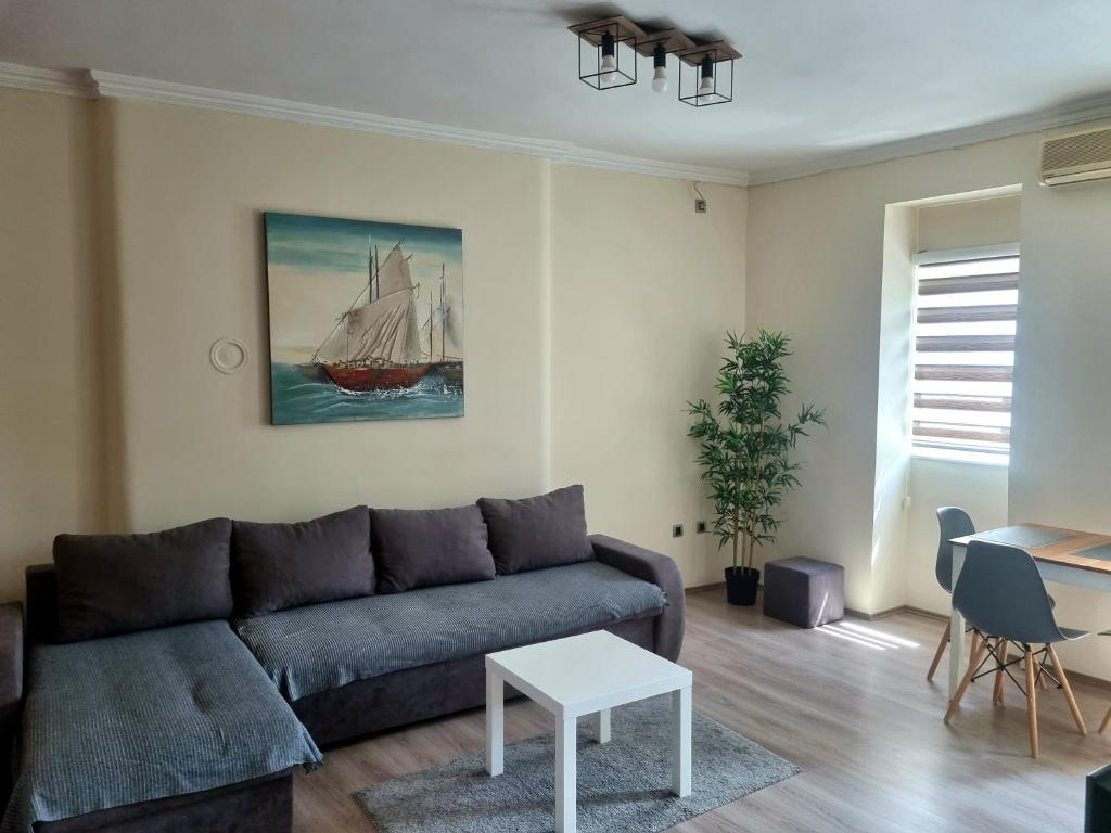 ein Wohnzimmer mit einer Couch und einem Segelboot-Gemälde in der Unterkunft Dixy apartman in Belgrad