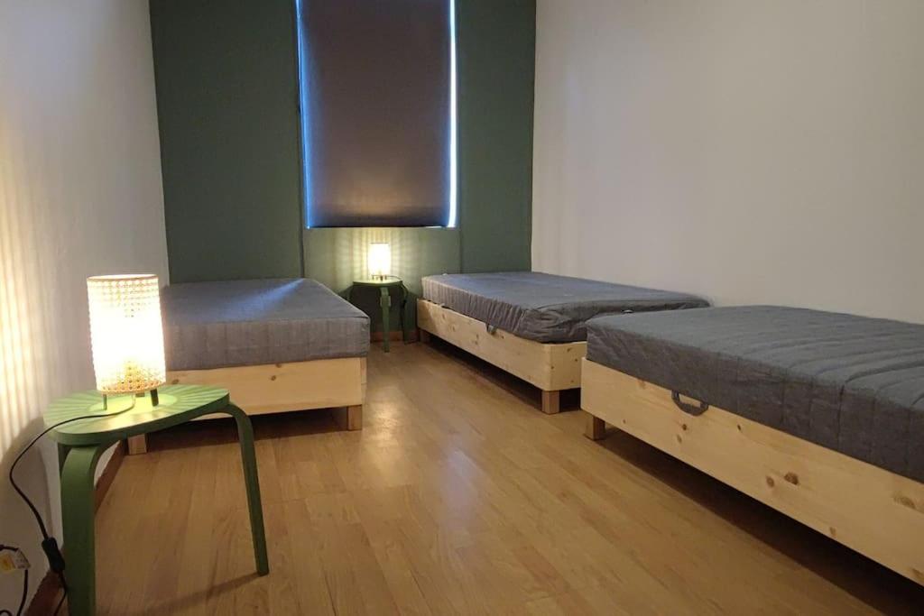 N°1 Annœullin - Appt spacieux - 2 Chambres في Annoeullin: غرفة بسريرين وطاولة بها مصباح