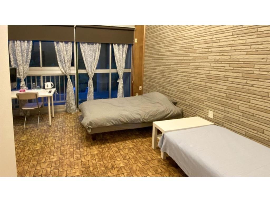 a bedroom with two beds and a brick wall at Forte "Hachijojima" - Vacation STAY 62479v in Hachijo