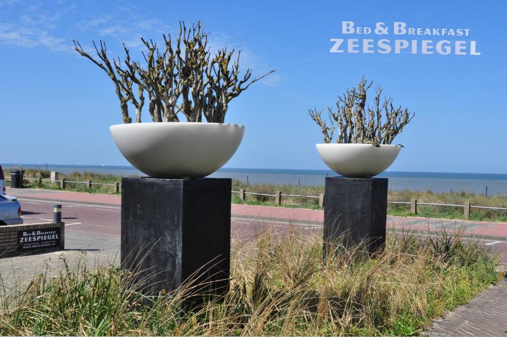 Deux gros bols blancs sur des poteaux noirs sur une route dans l'établissement B&B Zeespiegel, à Zandvoort