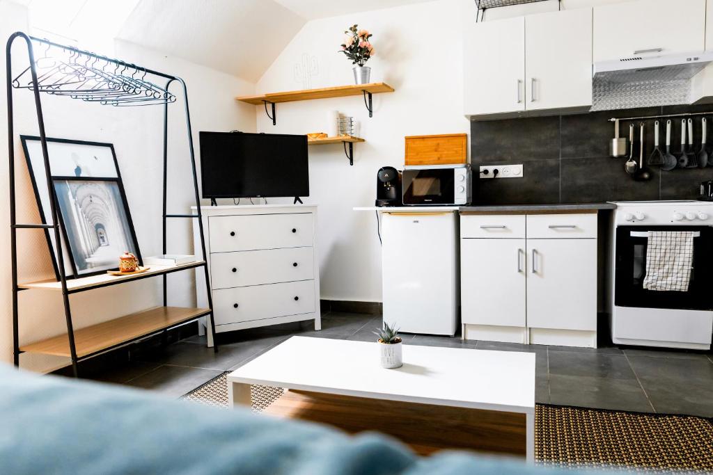 une cuisine avec des placards blancs et un mur noir dans l'établissement LMK, à Serris