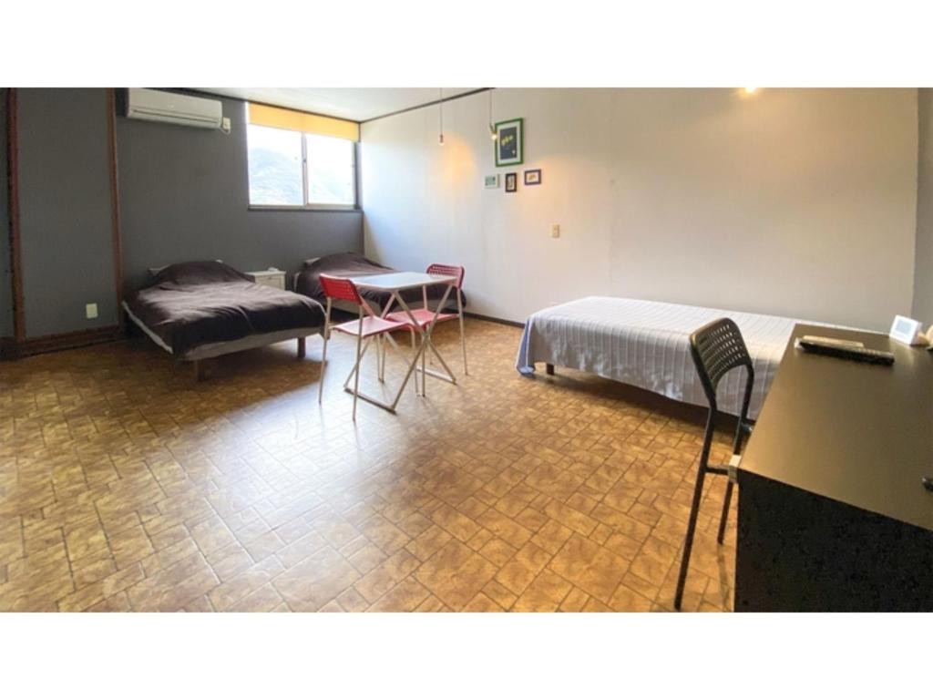 Zimmer mit 2 Betten, einem Sofa und einem Tisch in der Unterkunft Forte "Hachijojima" - Vacation STAY 62466v in Hachijō