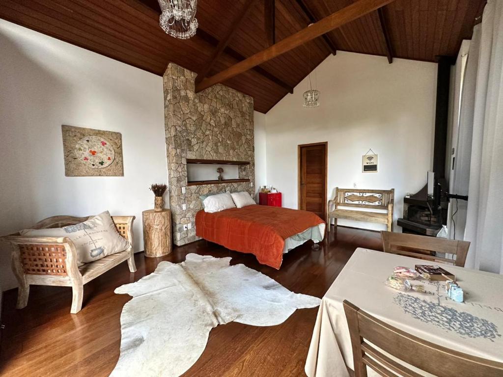 a bedroom with a bed and a living room at Zatara's Lodge - Monte Verde MG in Camanducaia