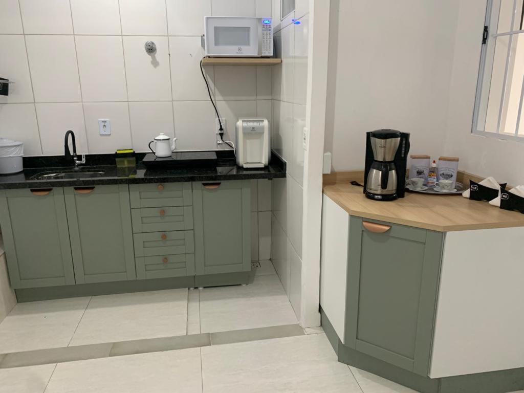 a small kitchen with green cabinets and a microwave at Suite 237 in Itanhaém