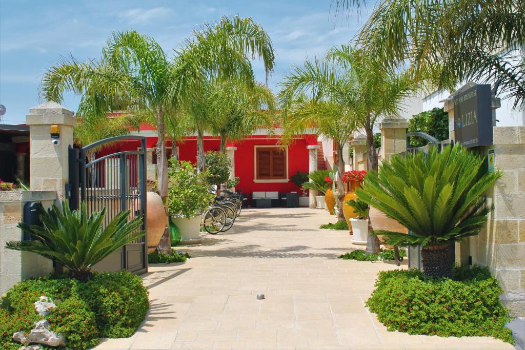 un patio con palmeras y un edificio rojo en B&B Lizia, en Porto Cesareo