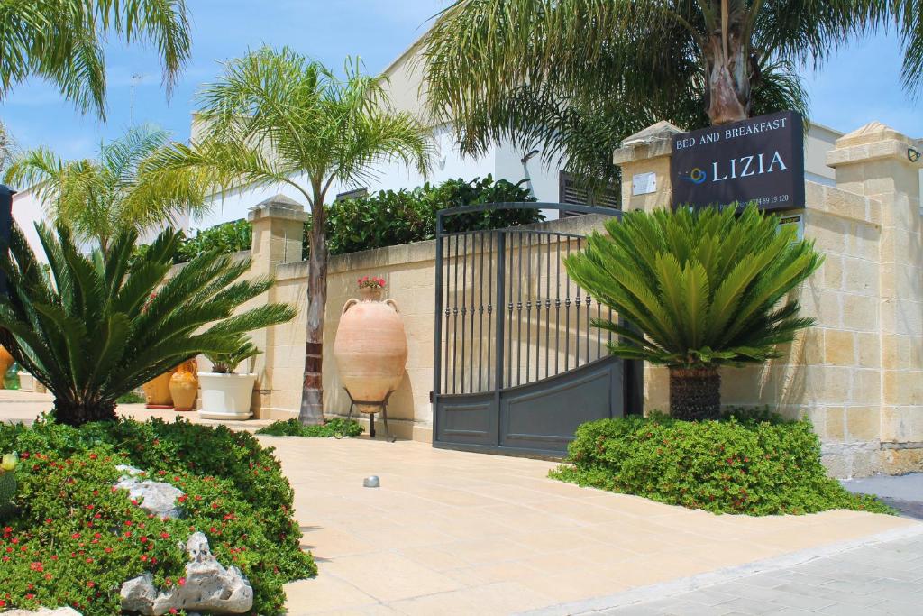 un cancello per una villa con palme e piante di B&B Lizia a Porto Cesareo