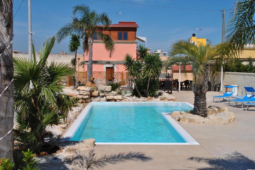 a swimming pool with palm trees and a house at Il Germoglio in Bisceglie