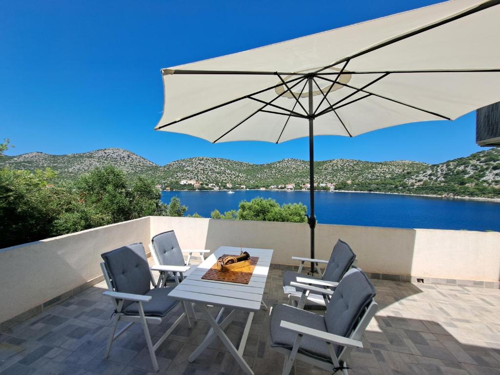 eine Terrasse mit einem Tisch, Stühlen und einem Sonnenschirm in der Unterkunft Apartman Portorus in Lastovo