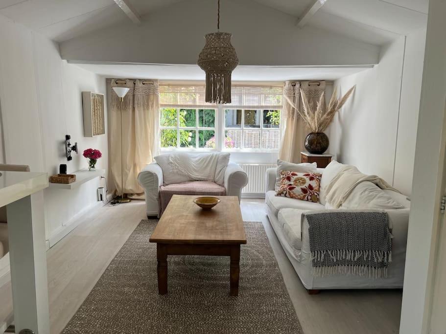 a living room with a white couch and a table at Huisje op de dijk in Kortenhoef