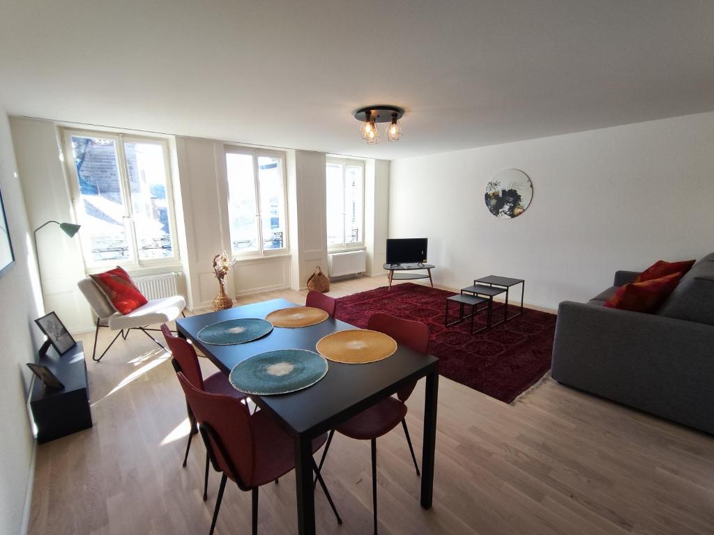 a living room with a table and chairs at Cosy appartement 1 chambre au coeur du bourg in Fribourg