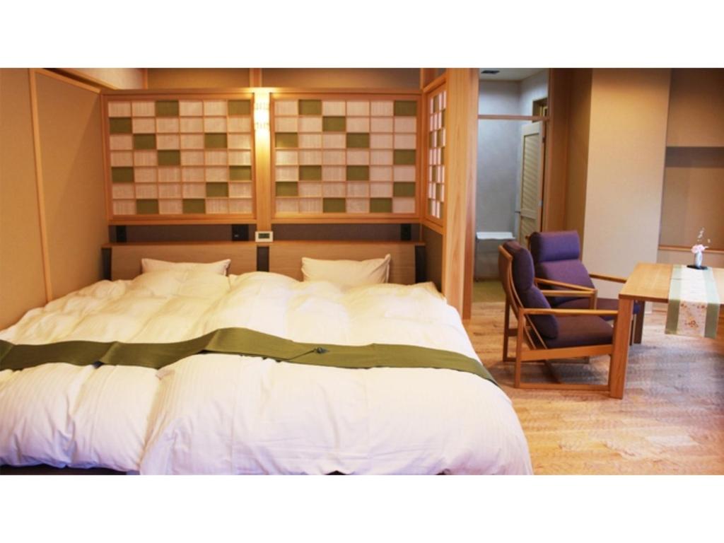 ein Schlafzimmer mit einem großen Bett, einem Tisch und einem Stuhl in der Unterkunft Unazuki Onsen Sanyanagitei - Vacation STAY 06553v in Kurobe