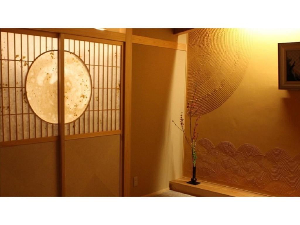 黒部市にあるUnazuki Onsen Sanyanagitei - Vacation STAY 06451vの花瓶が付いたガラスドアのある部屋