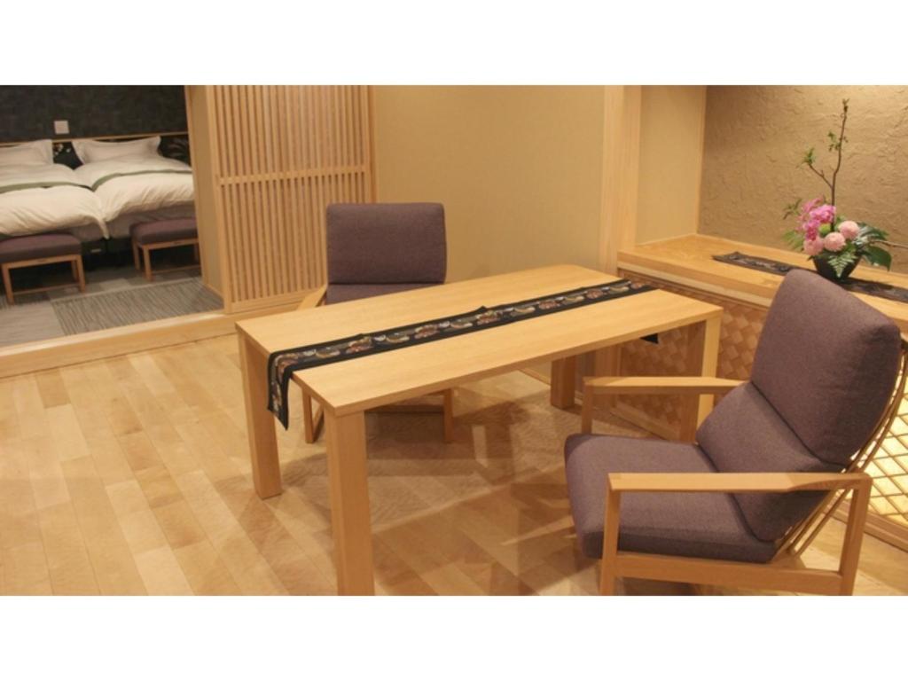 um quarto com uma mesa e duas cadeiras e uma cama em Unazuki Onsen Sanyanagitei - Vacation STAY 06433v em Kurobe