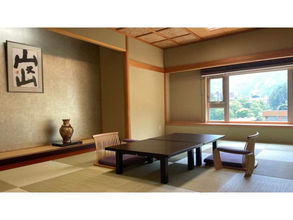 ein Esszimmer mit einem Tisch, 2 Stühlen und einem Fenster in der Unterkunft Unazuki Onsen Sanyanagitei - Vacation STAY 06557v in Kurobe