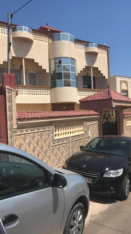 twee auto's geparkeerd voor een gebouw bij Sfiha/Hoceima huis in Al Hoceïma