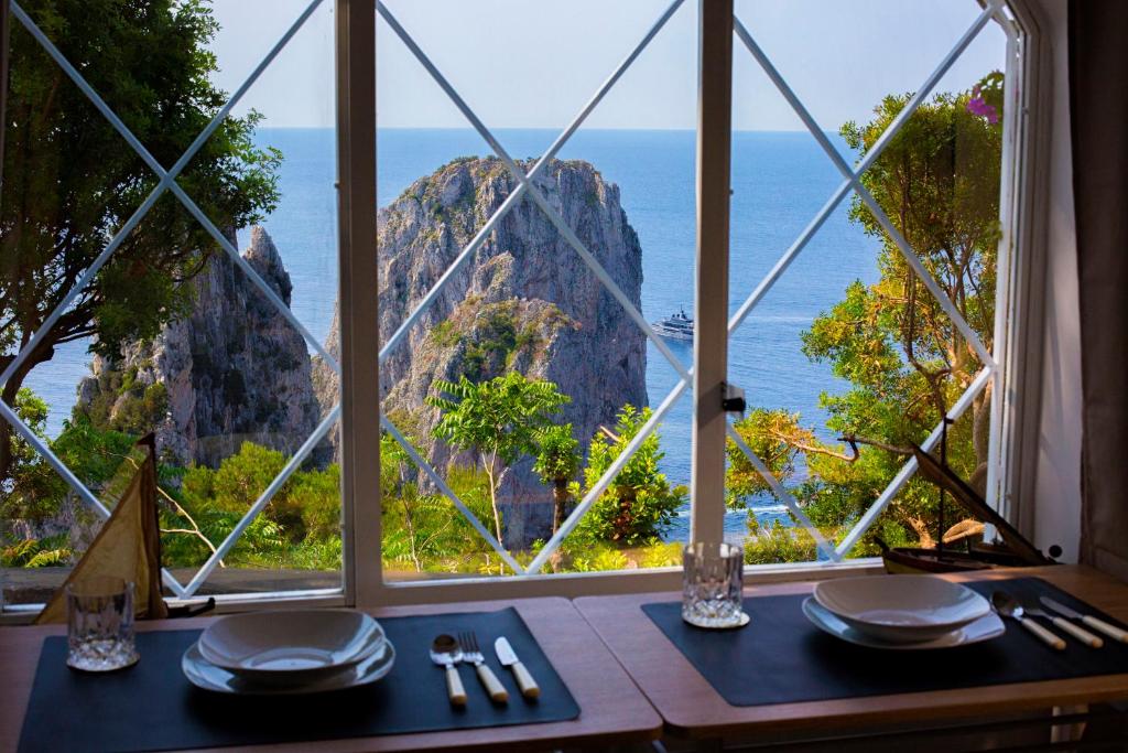 a table with a view of the ocean from a window at Faraglionensis MonaconeHouse Apartment in Capri