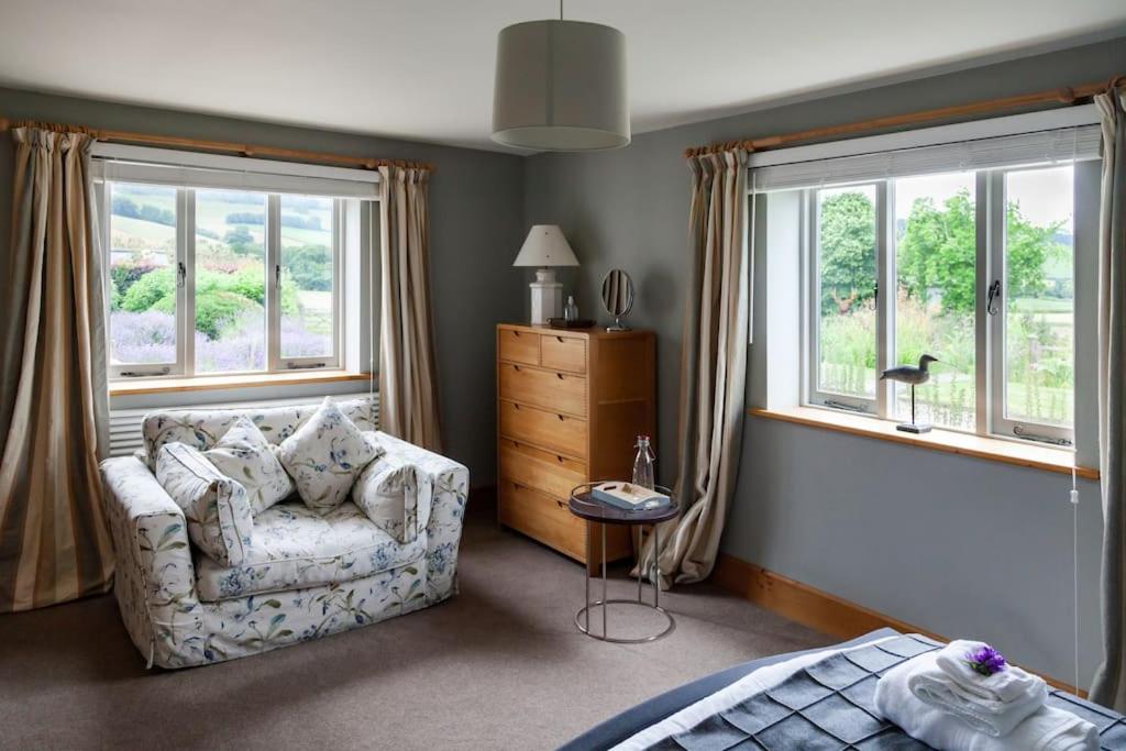 a living room with a couch and two windows at Stunning lodge in idyllic rural Herefordshire in Dorstone