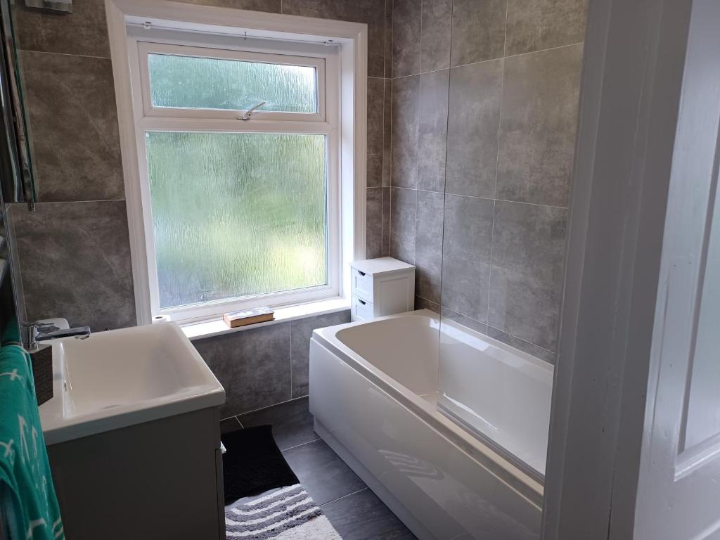 a bathroom with a tub and a sink and a window at 46 Linden Road in Scalby