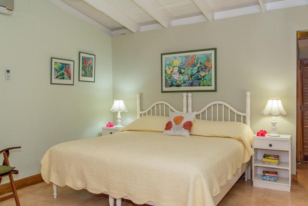 a bedroom with a white bed with two tables and two lamps at Sunny Vacation Villa No 8 in Mandeville