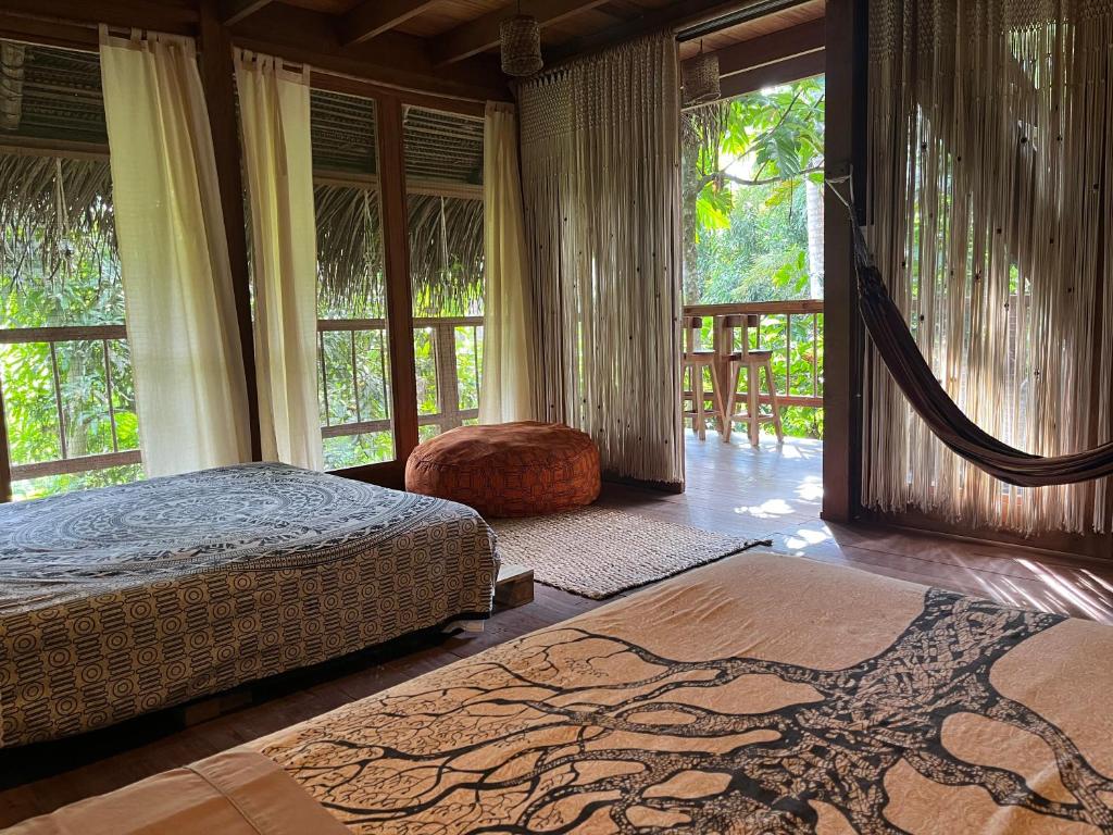 PUQIO ECOLODGE في تارابوتو: غرفة نوم بسريرين ونوافذ كبيرة