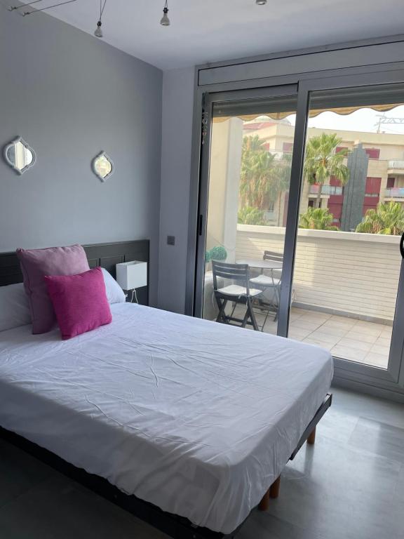 una camera da letto con balcone e letto con cuscini rosa di Fabulous Apartment with large pool near beach a Denia