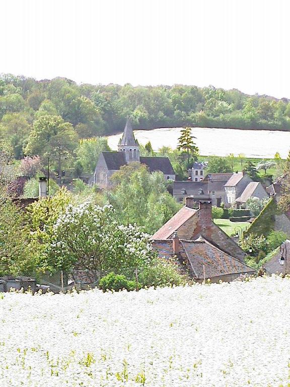 un groupe de maisons sur une colline avec un champ dans l'établissement Maison de Village Vexin site classé 1h Paris et Normandie grand jardin, à Reilly