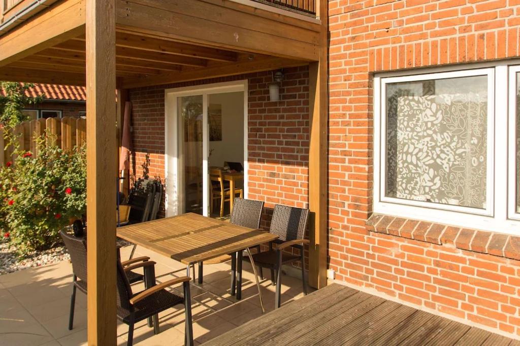 eine Terrasse mit einem Holztisch und Stühlen an einer Ziegelwand in der Unterkunft Charmante 3 Zimmer WHG mit Terrasse in Scharbeutz