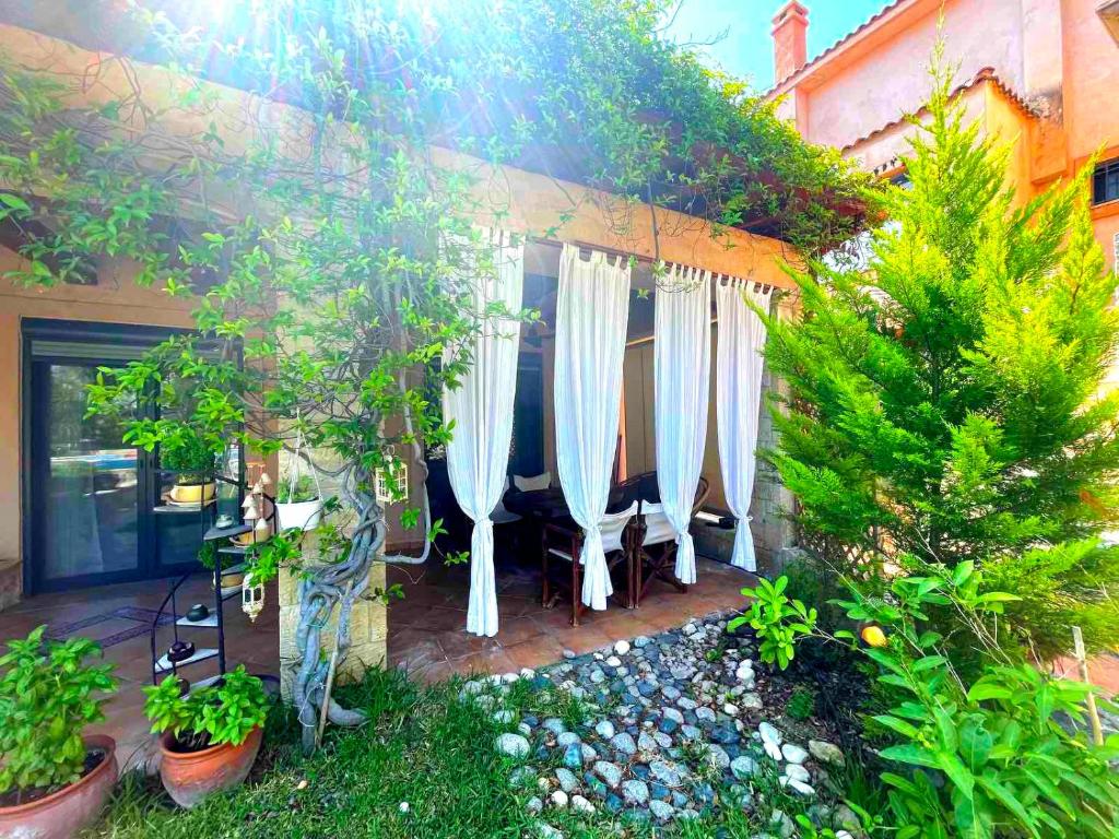 a patio with white umbrellas and trees and plants at Ariel's beach house in Pefkohori in Pefkohori